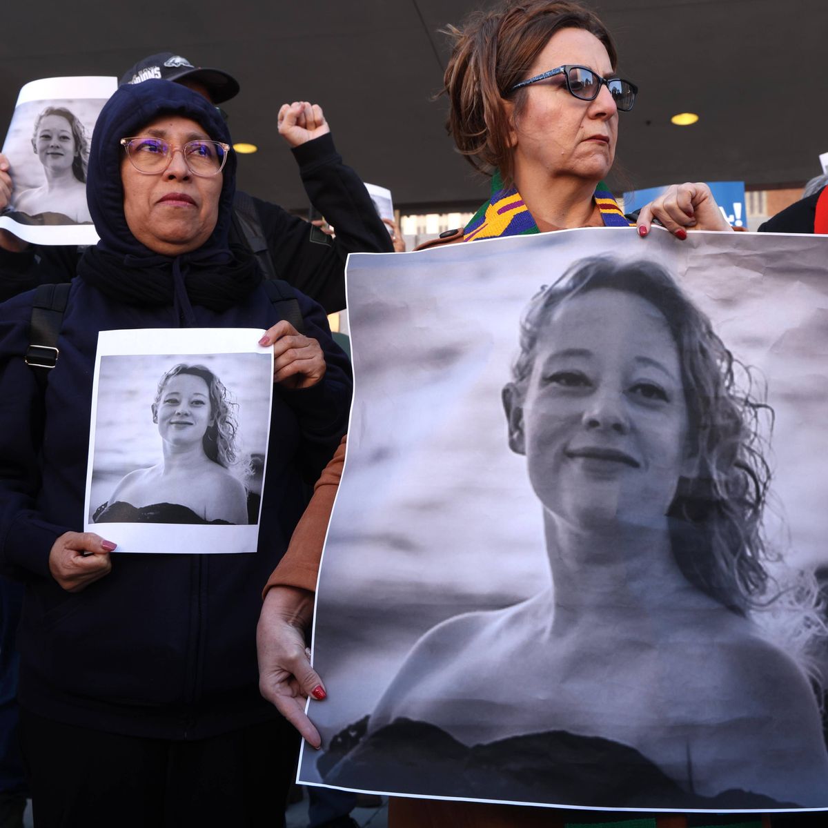 Protesters hold photos of Renee Good