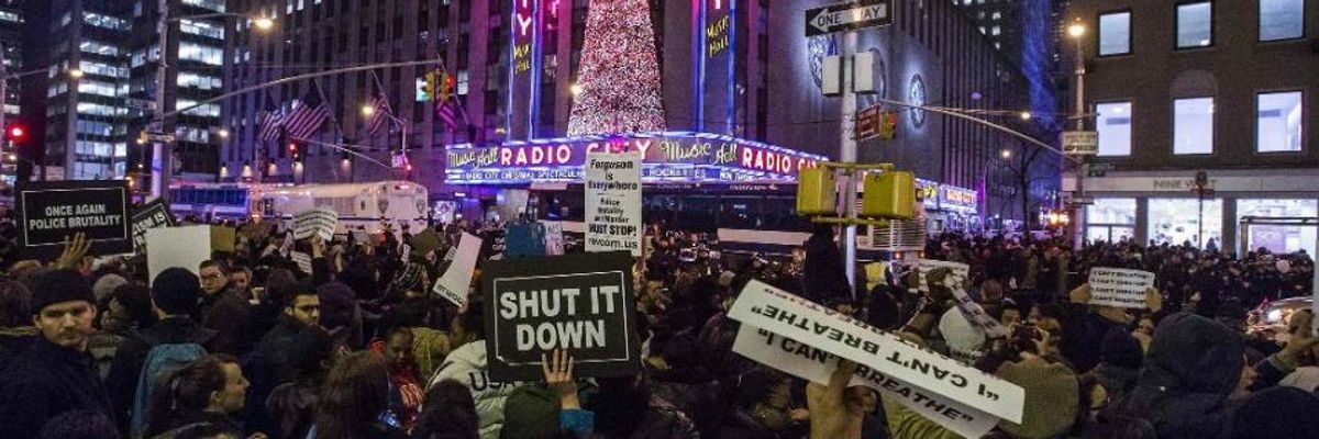 Protesters hold placards as they demand justice for the death of Eric Garner, while marching past Radio City Music Hall in the Manhattan borough of New York December 3, 2014.