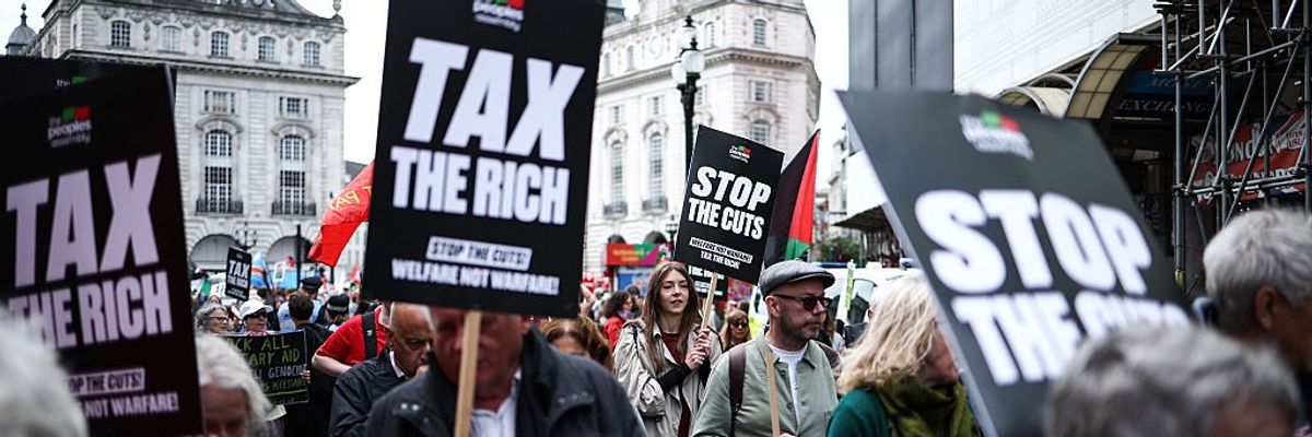 Protesters hold placards calling for higher taxes on the rich and an end to austerity
