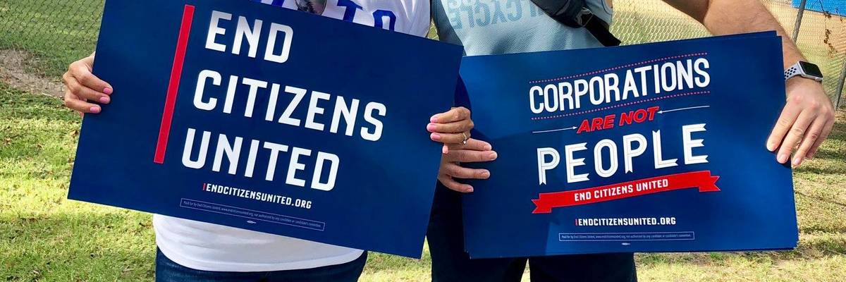 Protesters hold signs calling for an end to Citizens United and corporate personhood