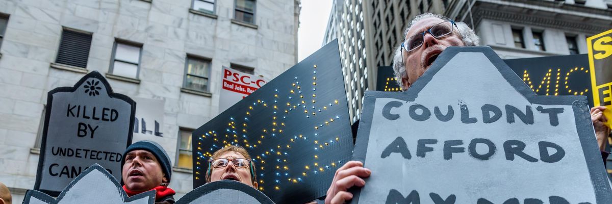 Protesters hold signs denouncing the Republican Party's Tax Cuts and Jobs Act outside the New York Stock Exchange on December 19, 2017.