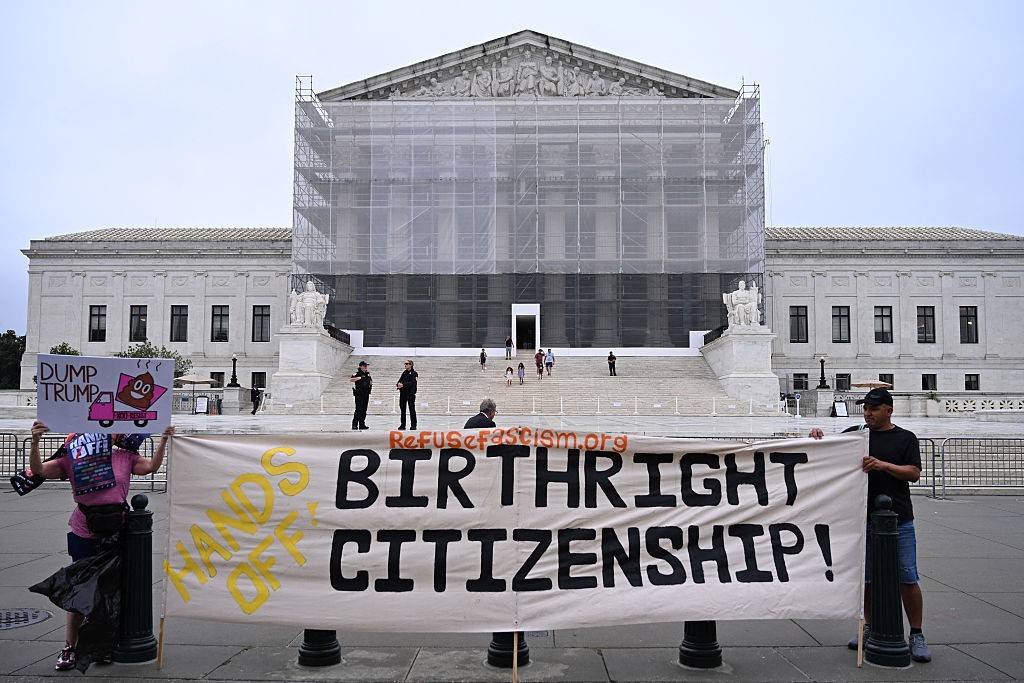 Protesters hold signs reading, "Hands off birthright citizenship" outside the Supreme Court.