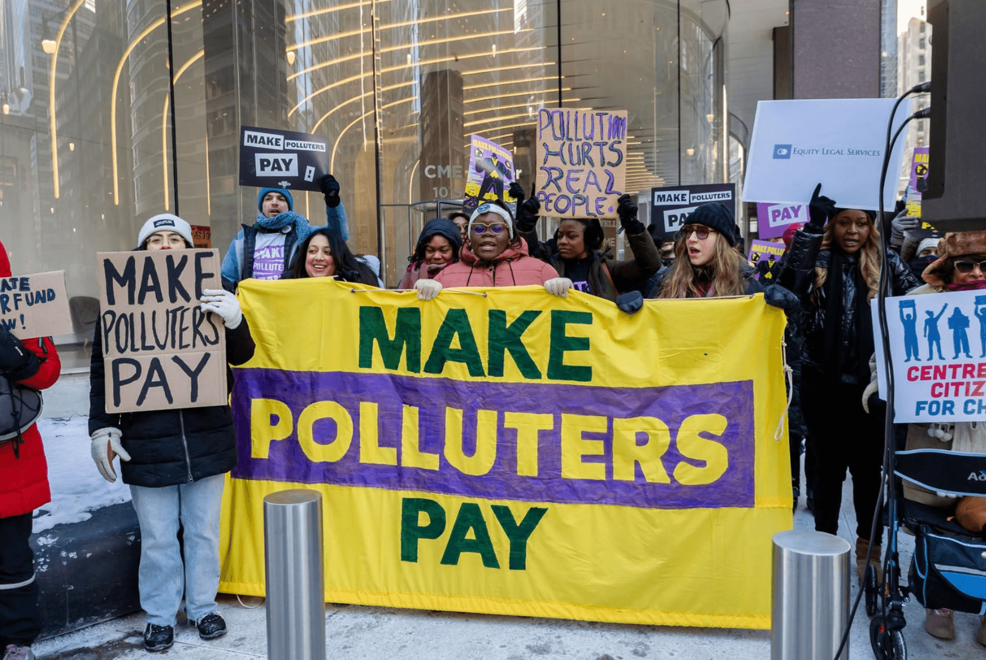 Protesters hold signs reading "make polluters pay"