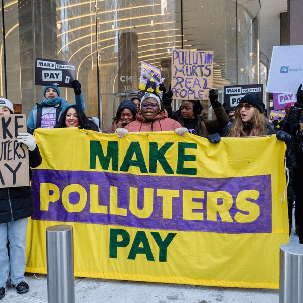 Protesters hold signs reading "make polluters pay"