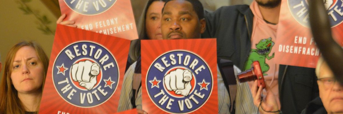 protesters hold signs reading "restore the vote"