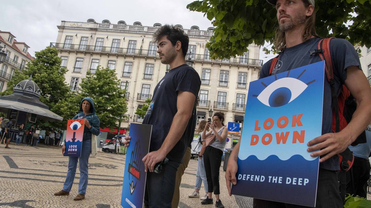 Protesters hold signs to demand an end to deep-sea mining