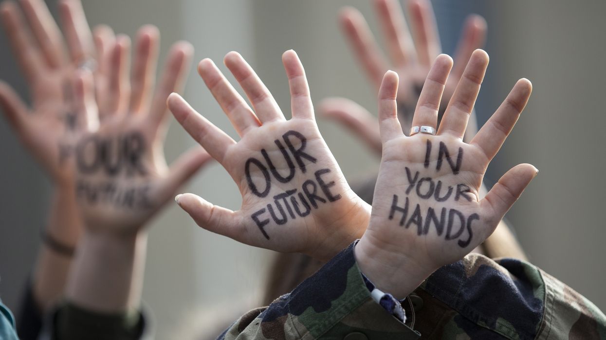 Protesters hold up hands painted with "Our Future in your hands."