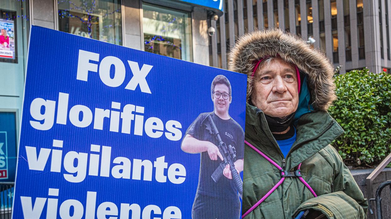 Protesters holds sign featuring Kyle Rittenhoouse. The sign says: "FOX glorifies vigilante violence"