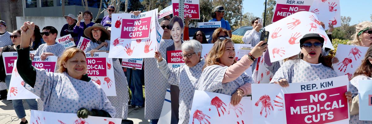 Protesters in hospital gowns hold signs reading, "No Medicaid cuts."