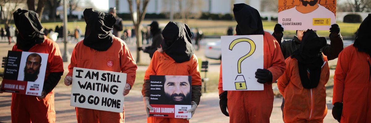 Protesters in orange jumpsuits and black hoods demand GITMO's closure