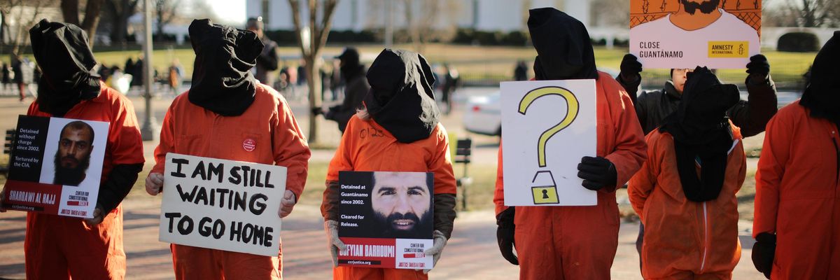 Protesters in orange jumpsuits and black hoods demand GITMO's closure 