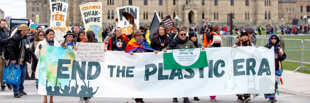 Protesters in Ottawa carry sign saying," End the Plastic Era."