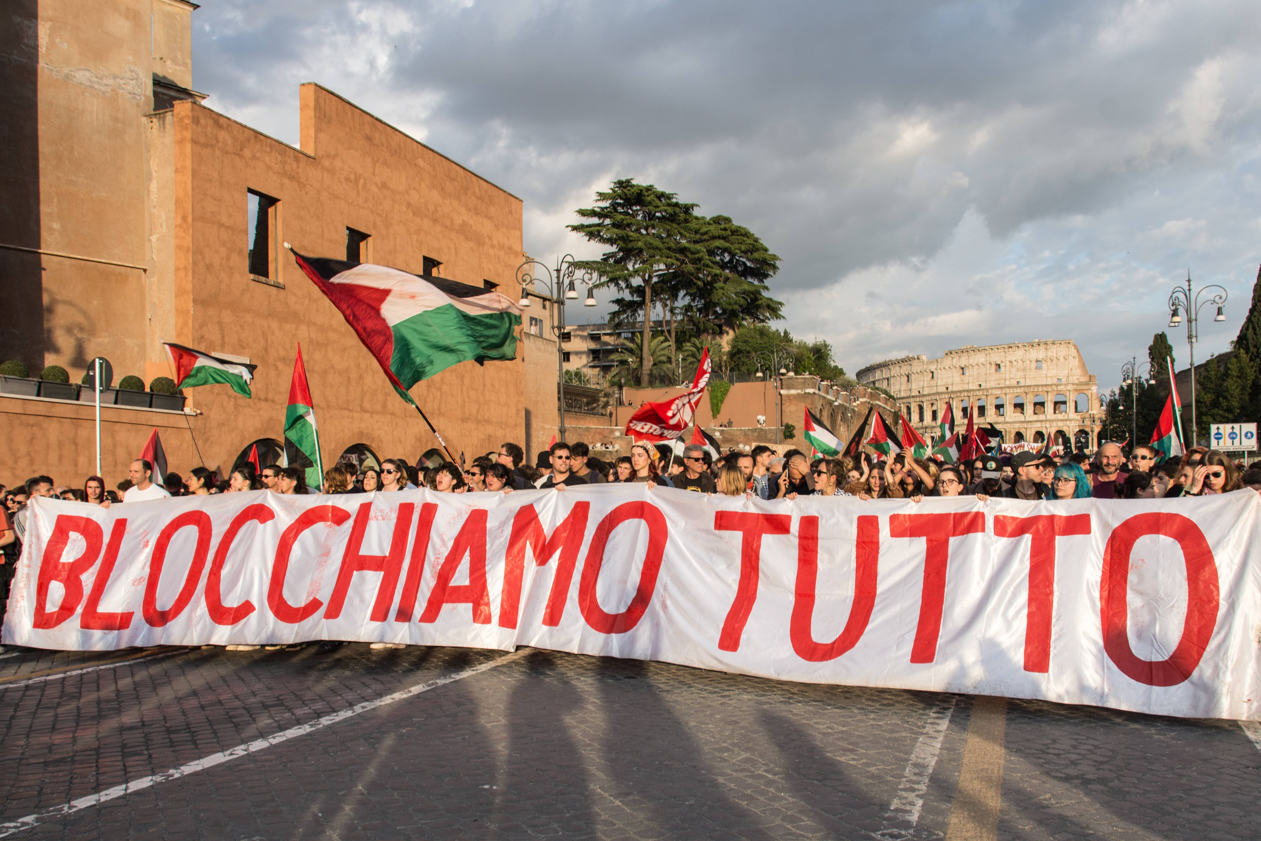 Protesters in Rome hold a banner reading "block everything" as they march near the Colisseum
