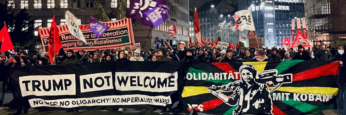 Protesters march in Zürich at night under a banner saying "Trump Not Welcome"