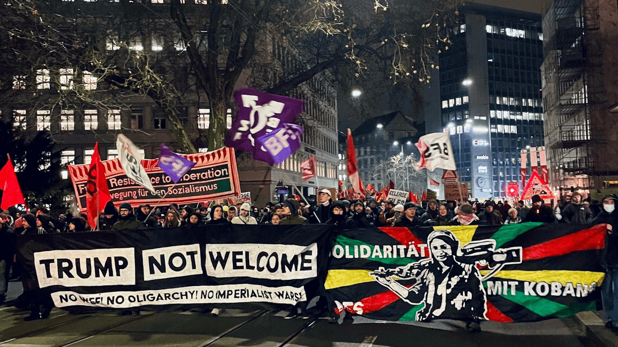 Protesters march in Zürich at night under a banner saying "Trump Not Welcome"