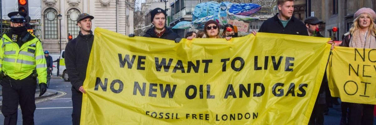 Protesters march with an anti-fossil fuel banner during the...