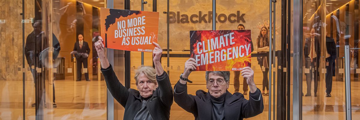 Protesters sit outside BlackRock H!Q holding signs reading, "No more business as usual" and "Climate emergency."