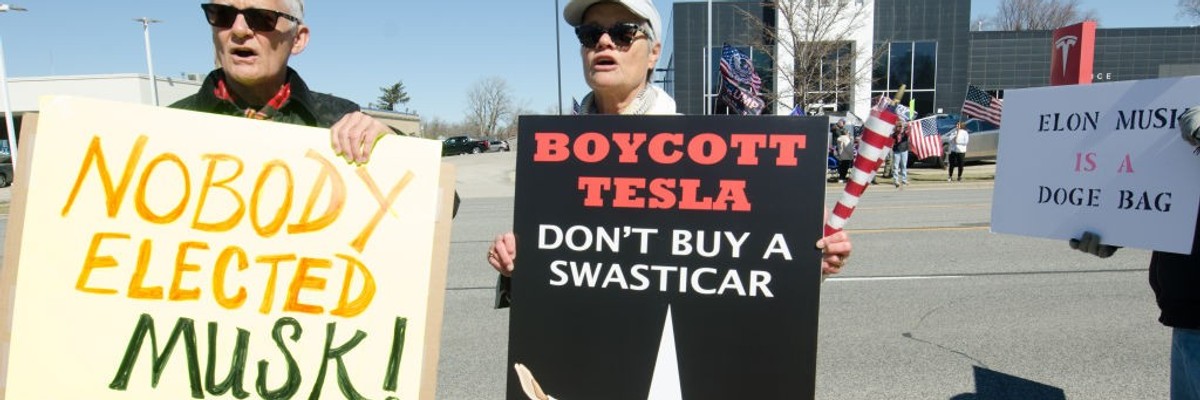 Protesters stand outside a Tesla car dealership