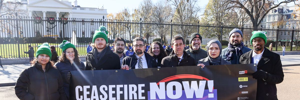 Protesters stand outside the White House with a sign saying, "Ceasefire now!"