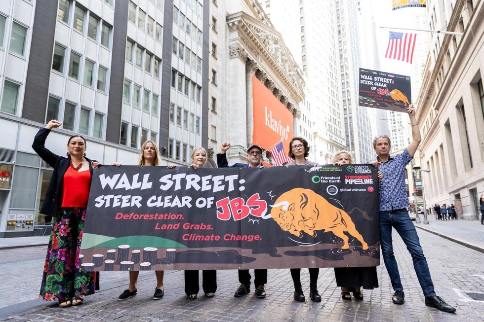 Protesters stand with a sign calling on Wall Street to stop investing in JBS.