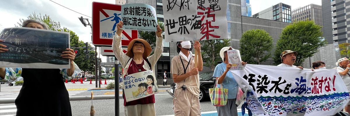 Protesters stand with signs opposing the Fukushima water release. 
