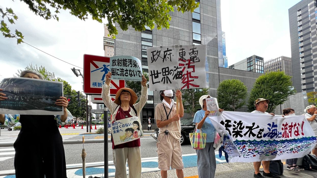 Protesters stand with signs opposing the Fukushima water release.