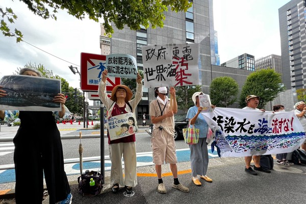 Protesters stand with signs opposing the Fukushima water release.