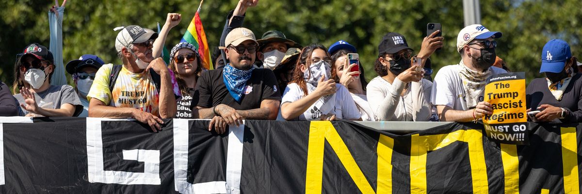 protestors stand behind a banner