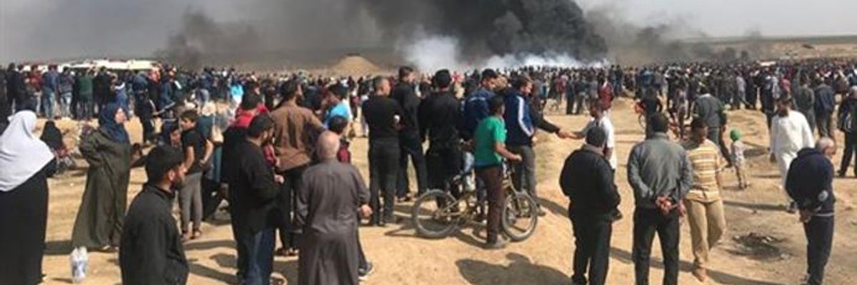 Protests along the Israel-Gaza border with smoke in the distance.