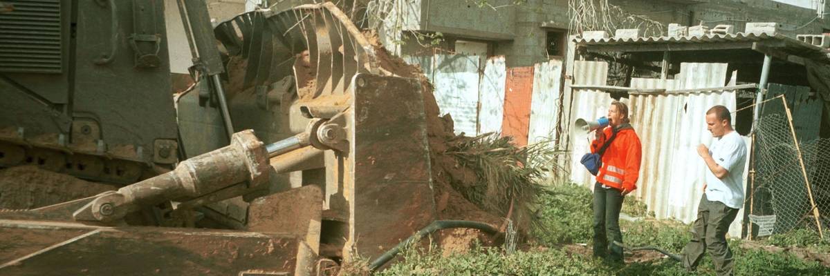 Rachel Corrie stands in front of bulldozer.