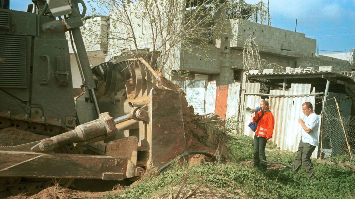 Rachel Corrie stands in front of bulldozer.