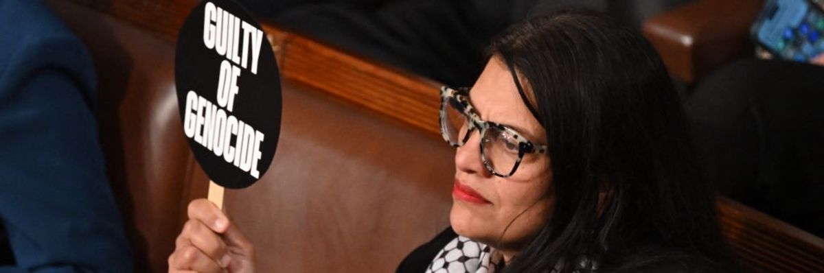 Rashida Tlaib holds a sign saying "guilty of genocide"