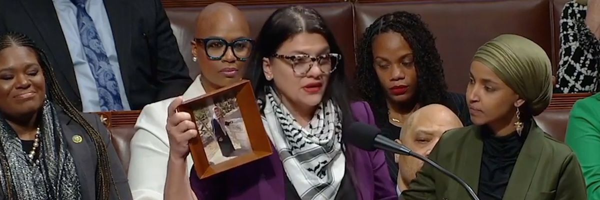 Rashida Tlaib, wearing a kaffiyeh, holds a photo of her Palestinian grandmother.