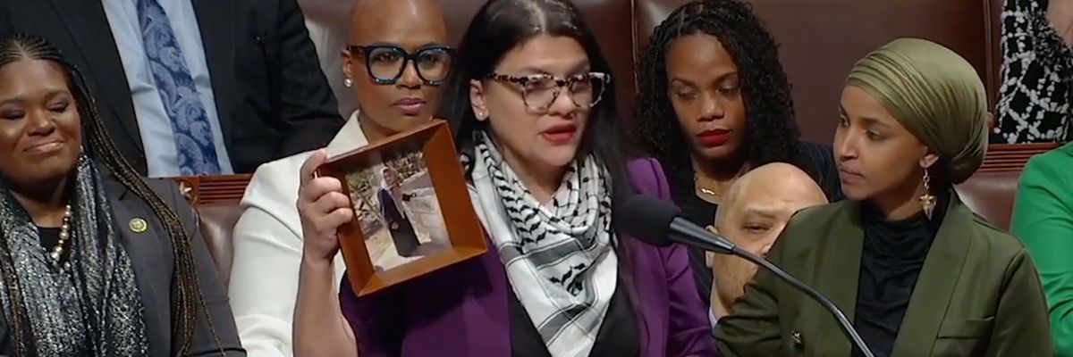 Rashida Tlaib, wearing a kaffiyeh, holds a photo of her Palestinian grandmother.