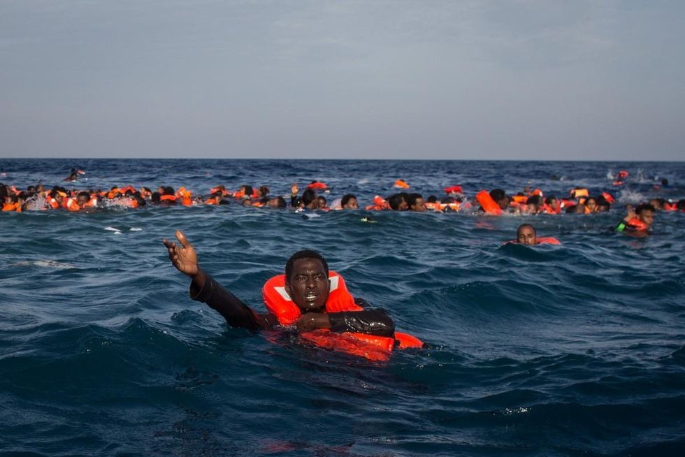 Refugees are seen swimming and yelling for assistance after a wooden boat bound for Italy carrying more than 500 people capsized on May 24, 2017 off Lampedusa, Italy. (Photo: Chris McGrath/Getty Images)