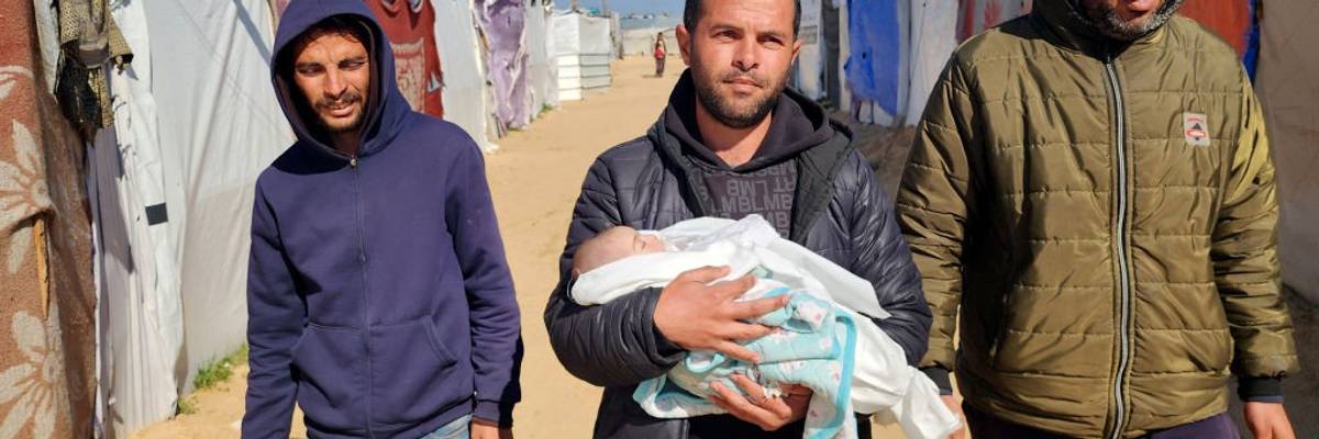Relatives hold a Palestinian baby who died from exposure to cold in a Gaza refugee camp