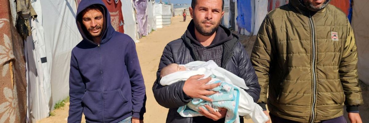 Relatives hold a Palestinian baby who died from exposure to cold in a Gaza refugee camp