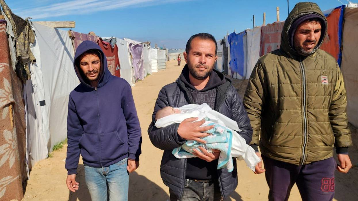 Relatives hold a Palestinian baby who died from exposure to cold in a Gaza refugee camp