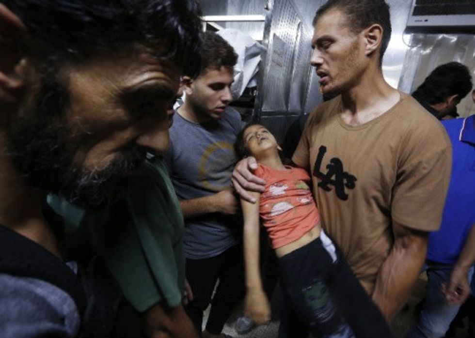 Relatives hold the body of a Palestinian girl in the morgue at Al-Shifa Hospital in Gaza City
