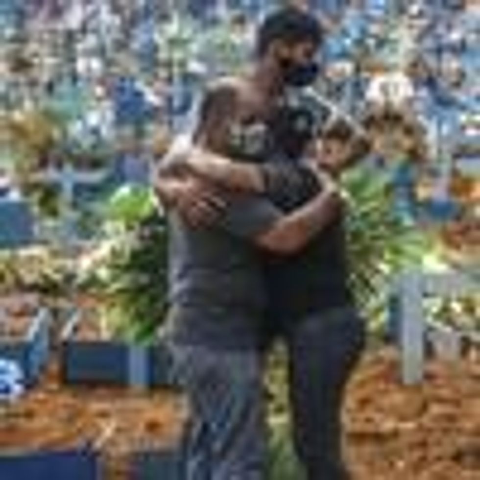 Relatives of a Brazilian Covid-19 victim embrace in a cemetery built for the mass burial of people killed by the pandemic in Manaus, Amazonas. (Photo: Andre Coelho/Getty Images)