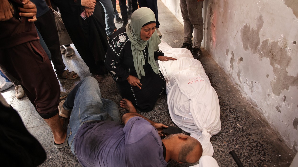 Relatives react over the shrouded body of a person killed in an Israeli strike