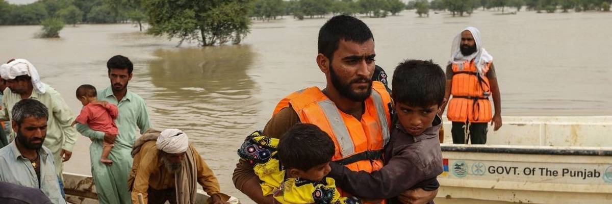 Rescue workers help evacuating flood-affected people from their flood hit homes following heavy monsoon rains in Rajanpur district of Punjab province on August 27, 2022.