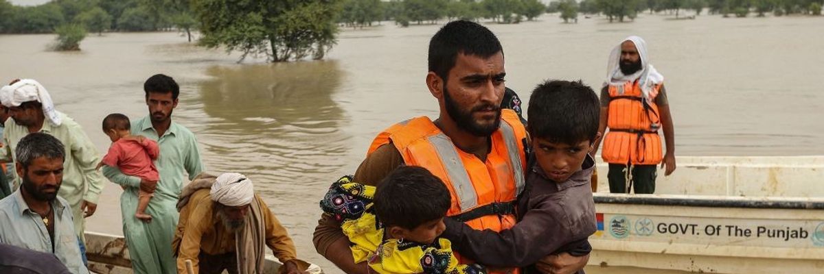 Rescue workers help evacuating flood-affected people from their flood hit homes following heavy monsoon rains in Rajanpur district of Punjab province on August 27, 2022.