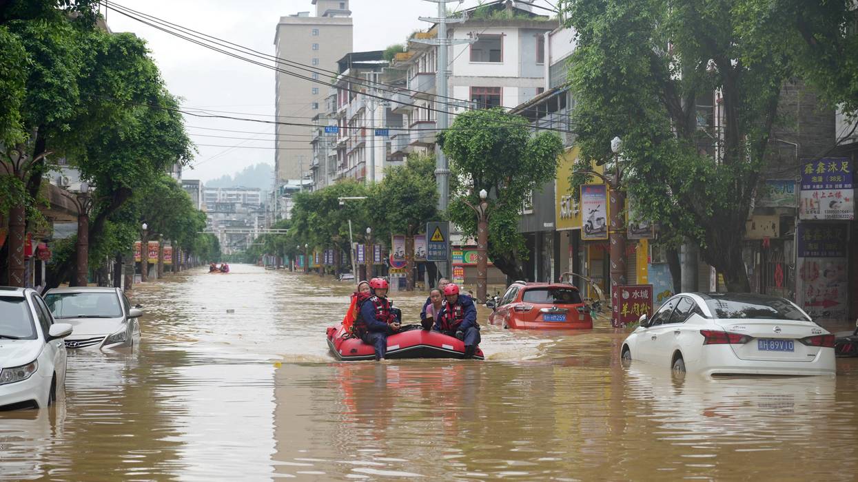 Rescuers help evacuate residents from a flooded street in Rongjiang
