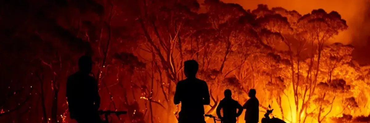 Residents look on as flames burn through bush in Australia