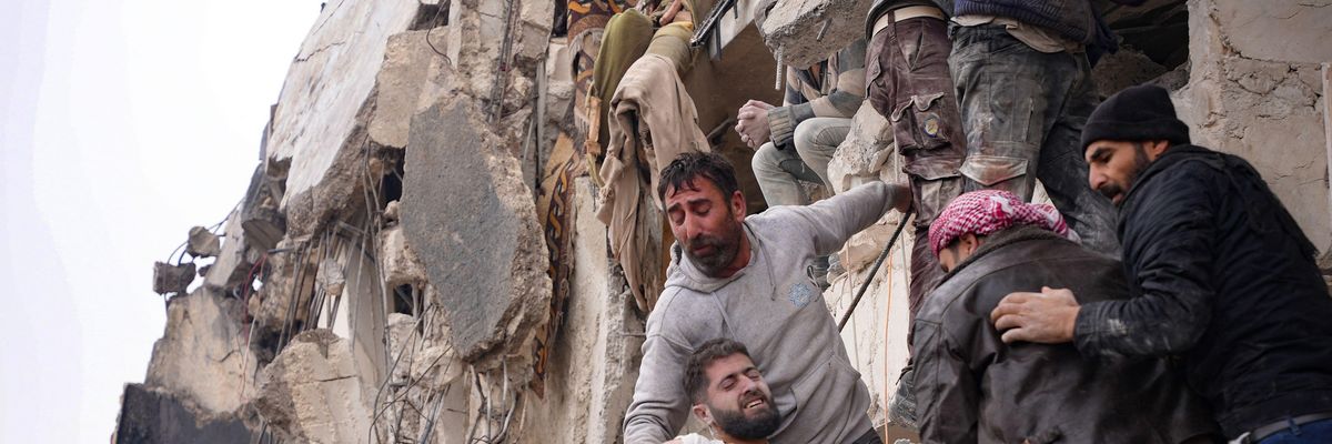 Residents retrieve an injured man from the rubble of a collapsed building following an earthquake in the town of Jandaris, Syria
