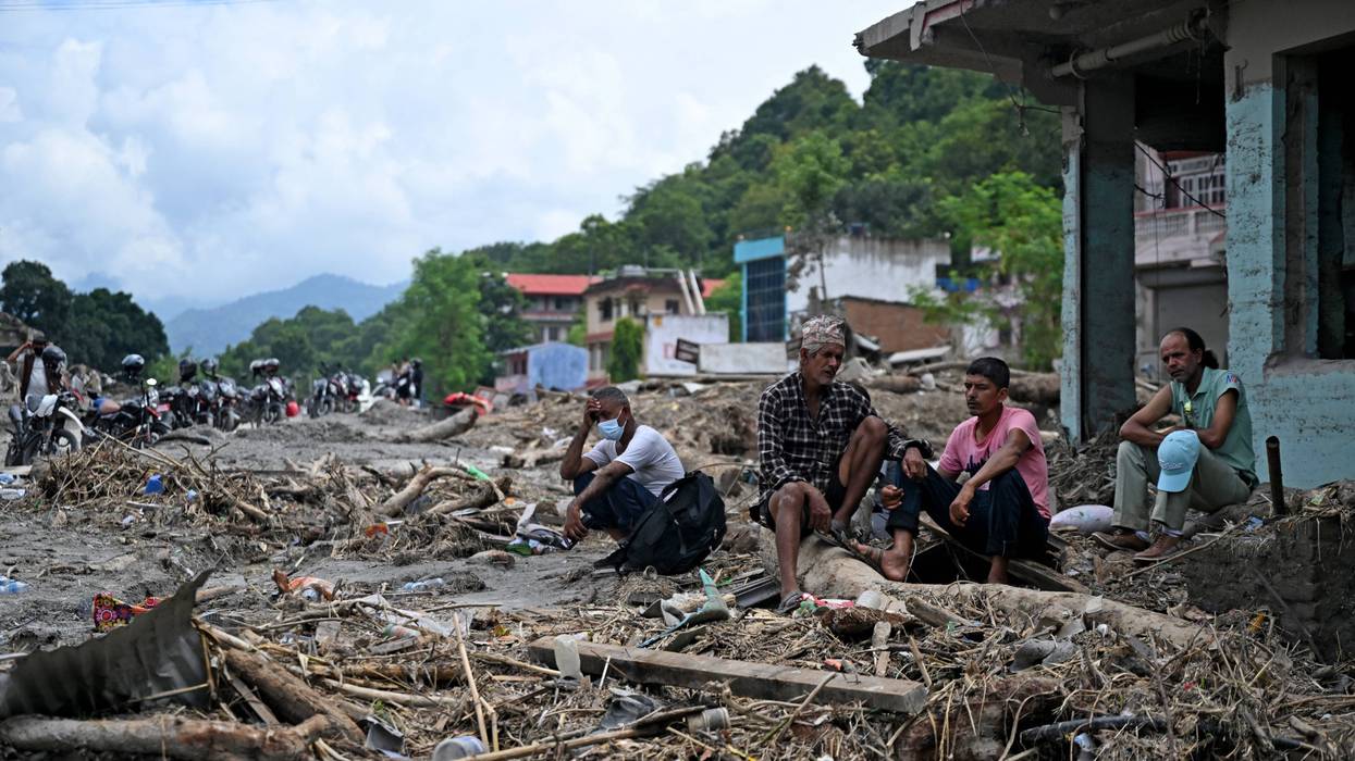 Residents sit beside debris as they salvage some belongings