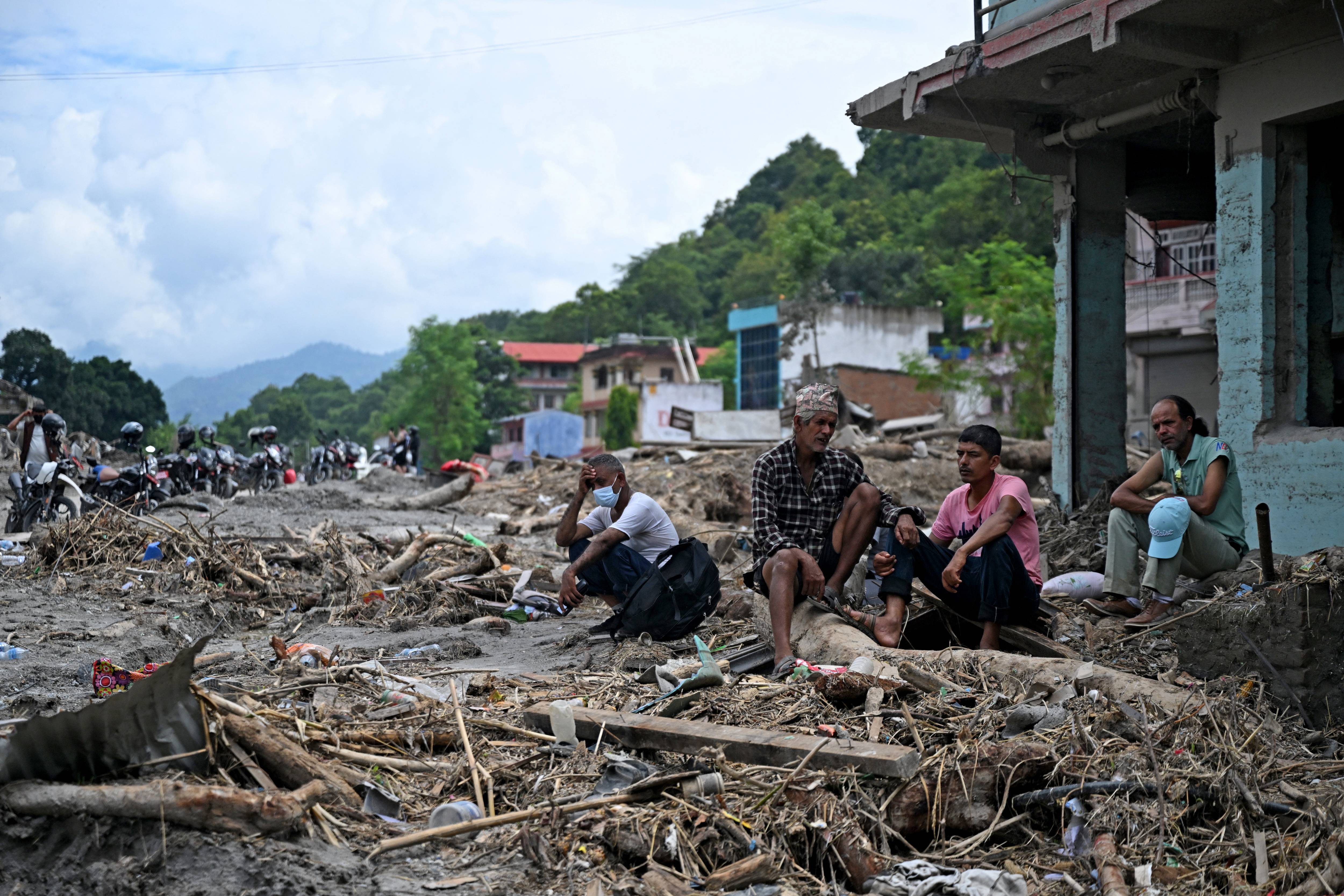 Residents sit beside debris as they salvage some belongings