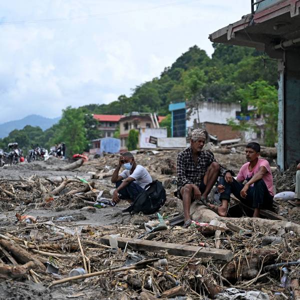 Residents sit beside debris as they salvage some belongings