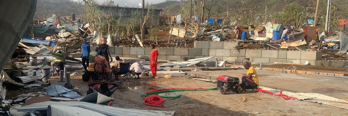 residents sitting among piles of debris of metal sheets and wood after homes were destroyed by the cyclone Chido